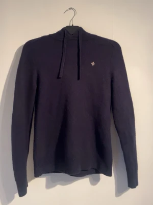 Mörkblå hoodie med broderad detalj - Marinblå merinoulls hoodie från morris. Krympt i tvätten, var storlek m från början men passar xs bättre nu
