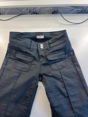 Svarta bootcut nelly jeans - Snygga svarta jeans med bootcut passform och markerade pressveck framtill. Klassisk femficksmodell med knapp- och dragkedjestängning. Jeansen har en modern look och passar perfekt till en trendig stil.
