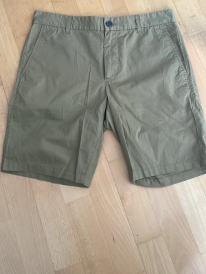 Beiga bomullsshorts med fickor - Klassiska beiga shorts i bomull med normal passform. Shortsen har sidofickor fram och två bakfickor med knappstängning. Perfekta för varma dagar och enkel att matcha med olika stilar.