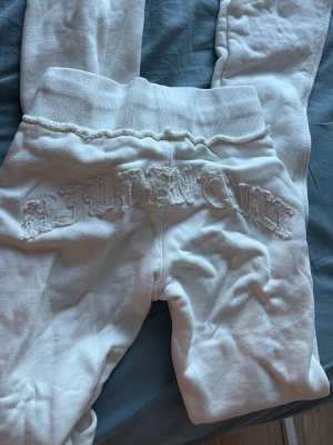 Vita leggings med broderad text - Säljer ett par vita leggings med bred resår i midjan och broderad text på baksidan. Materialet är mjukt och stretchigt, perfekt för en avslappnad look. Passar dig som gillar streetwear och vill ha något bekvämt men ändå snyggt.
