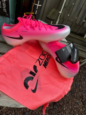 Nike Mercurial vapor 17 elite - Säljer ett par grymma Nike Mercurial fotbollsskor i en riktigt snygg rosa färg med svarta detaljer. Skorna har en låg profil, snörning och är tillverkade i ett lätt syntetmaterial med textur för bättre bollkontroll. Kommer med matchande rosa påse.