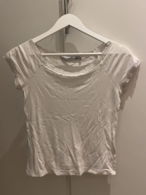 Vit topp med spetsdetaljer - Enkel T-shirt från lager 157 med fin spetsdetalj. Säljer eftersom att det inte passar mig som jag hade velat.