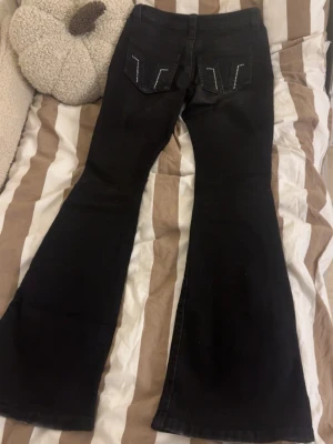 Svarta bootcut jeans med detaljer - Säljer ett par svarta bootcut jeans med snygga detaljer på bakfickorna. Väldigt bra skick då jag inte använt som alls mycket. Jag är öppen för alla frågor så bara skicka ett sms!💕