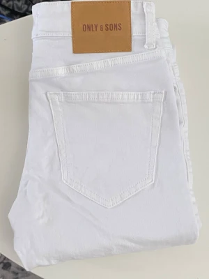 Vita jeans från ONLY & SONS - Snygga vita jeans från ONLY & SONS med klassisk femficksdesign och raka ben. Jeansen har en stilren look och är perfekta för dig som vill sticka ut med en fräsch och modern stil. Materialet är mjukt och bekvämt, vilket gör dem lätta att bära hela dagen.