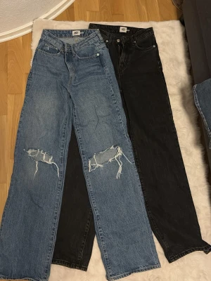 två par  jeans med hög midja och raka  - Säljer ett par svarta och blåa jeans med rak passform och hög midja. Jeansen har klassisk femficksdesign och är tillverkade i ett kraftigt denimtyg. Perfekta för en avslappnad och trendig look.