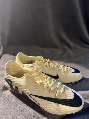 Nike gröna och svarta fotbollsskor - Säljer ett par gröna fotbollsskor från Nike med stora svarta swoosh-loggor på sidan och tån. Skorna har snörning och låg profil, samt en lätt ovandel i syntetmaterial för bra bollkontroll. Perfekta för dig som vill ha stilrena och snabba skor på planen. Helt nya har använt en gång. Hör av er vid intresse inga prisförslag är dumma 