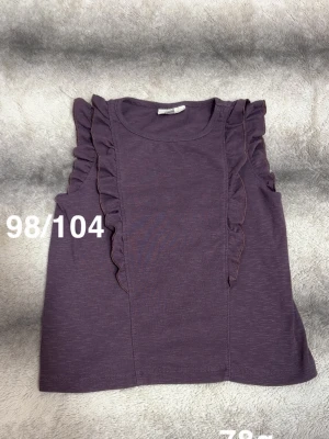 Lila ärmlös topp med volang - Superfin lila ärmlös topp med volangdetaljer längs axlarna. Perfekt för dig som gillar en söt och trendig stil. Mjuk och skön att bära, passar till många olika outfits.🌸Fint använt skick. Storlek 98/104