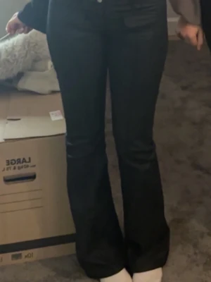 Svarta bootcut jeans från Nelly  - Säljer ett par svarta bootcut jeans från Nelly i skinnmateriall. De är den gamla modellen därav finns den inte kvar på hemsidan💕