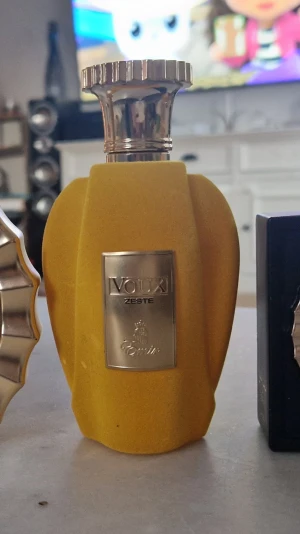 Paris Corner Voux Zeste - Vouxi Zeste parfym från Emir i en unik, matt gul flaska med guldfärgat metallock och metallskylt framtill. Flaskan har en modern, skulptural form som sticker ut på hyllan och ger en lyxig känsla.  Ca 90 mo kvar