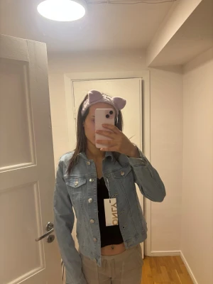 Ljusblå jeansjacka från ONLY - Säljer en ljusblå jeansjacka från ONLY i klassisk denimstil. Jackan har knappar framtill, två bröstfickor med lock och en snygg, kort passform. Perfekt att slänga över en topp för en cool look.