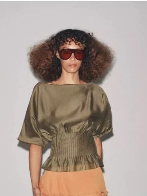 Ny Olivgrön satinblus med markerad midja - Trendig olivgrön blus i glansigt satintyg med bred, smockad midja och volangkant nedtill. Blusen har lös passform upptill och korta, vida ärmar som ger en avslappnad men chic look. Perfekt för dig som vill ha något unikt och stilrent. Ny med prislapp kvar . Slutsåld på hemsida, nypris 559kr