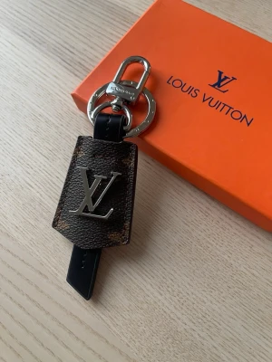  Vuitton nyckelring brun monogram - Säljer en exklusiv nyckelring från  Vuitton i brunt monogramläder med silverfärgad LV-logga och metallspänne. Perfekt accessoar för att piffa till väskan eller nyckelknippan. Kommer med original orange ask.