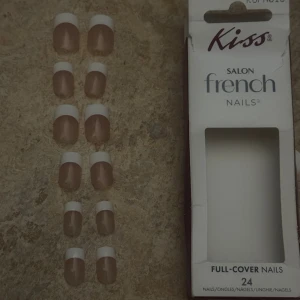 Kiss franska press-on naglar - Säljer ett set med Kiss Salon French press-on naglar. Naglarna har en klassisk fransk manikyr med naturlig rosa bas och vit tipp. Förpackningen innehåller 24 full-cover naglar i olika storlekar. Perfekt för dig som vill fixa snygga naglar snabbt och enkelt.