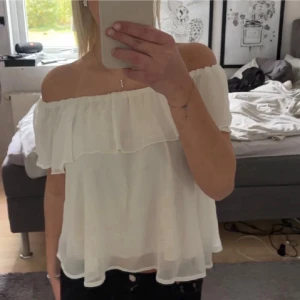 Vit offshoulder topp från Bik Bok - Säljer en superfin vit offshoulder topp från Bik Bok. Toppen har volangdetalj runt hela axelpartiet och är tillverkad i ett lätt, luftigt material som ger en flowy känsla. Perfekt för varma dagar och snygg att styla med jeans eller kjol.
