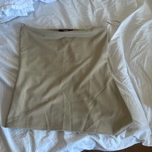 Beige tubtopp  - Säljer en stilren beige tubtopp från BikBok i storlek L. Toppen är axelbandslös och har en enkel, rak passform. Tillverkad i en mjuk blandning med återvunnen polyester som känns skön mot huden. Perfekt att matcha med jeans eller kjol för en clean look.