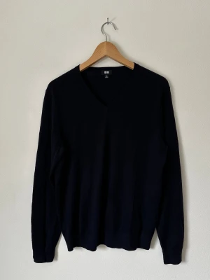 Mörkblå V-ringad stickad tröja Uniqlo - Klassisk mörkblå stickad tröja från Uniqlo med V-ringning och långa ärmar. Tröjan har en enkel och stilren design, perfekt att matcha med olika outfits. Tillverkad i mjukt material som känns skönt mot huden. 8B1