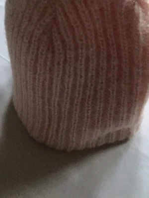 Rosa ribbstickad mössa - Mysig rosa ribbstickad mössa i mjukt material. Klassisk form med uppvikt kant och diskret mönster. Perfekt för att hålla värmen under kyliga dagar.