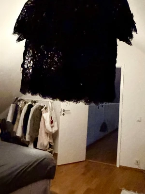 Svart spetsblus med kort ärm - Svart blus i spets med korta ärmar. Blusen har ett transparent, blommigt spetsmönster och fransig kant nertill. Storlek S. Bra skick även om den varit favorit.