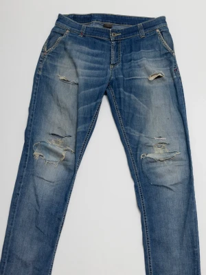 Dondup jeans  - Ett par blå jeans från Dondup med slitningar och hål på både fram- och baksida. Jeansen har klassisk femficksdesign, dragkedja och knapp i midjan samt raka ben. Perfekta för en avslappnad och trendig look. Passar W30 L32.
