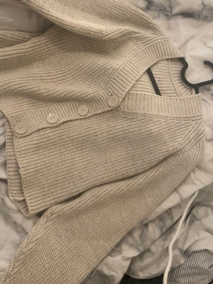 Beige stickad kofta med knappar - Snygg beige stickad kofta med fyra matchande knappar framtill.  Koftan är st xs men passar även S