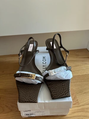 Bruna nya låga klackar från Nelly (oanvända)  - Helt nya klackskor från Nelly, storlek 40. De är 5 cm i klackhöjden m. justerbara remmar över foten och över ankeln. Endast testade en gång hemma, men köpte fel storlek och hann inte skicka tillbaka dem i tid så säljer dem - nyskick, i originalkartong. Kostar 499kr på Nelly men säljer för 200kr.