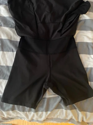 Svart sportig skort från Aone - Snygg svart skort från Aone med bred midjeresår och inbyggda shorts under kjolen. Tillverkad i ett stretchigt och mjukt material som passar perfekt för träning eller en aktiv dag. Två inbyggda fickor på sidorna.