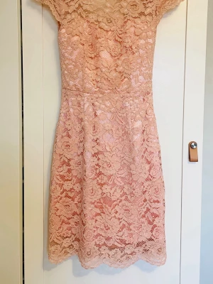 Ljusrosa spetsklänning By Malina stl S - Supersöt ljusrosa klänning från By Malina med vackert blommigt spetsmönster. Klänningen har korta ärmar, rund halsringning och figurnära passform. Öppen rygg. Perfekt för sommarens alla festliga tillfällen! Storlek S. 