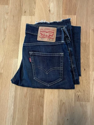 Levi's 511 mörkblå jeans W30 L32 - Säljer ett par klassiska Levi's 511 jeans i mörkblå denim. Modellen har smal passform och fem fickor, med den ikoniska röda Levi's-lappen på bakfickan och läderpatch i midjan. Perfekta för en stilren och avslappnad look.