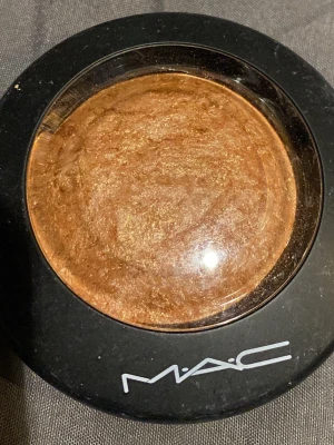 MAC shade GLOBAL GLOW  - Snygg bronzer från MAC i nyansen guld-brons med skimrande finish. Kommer i en rund svart dosa med genomskinligt lock. Perfekt för att ge ansiktet glow och värme. Mineralbaserad formula som ger en naturlig lyster.