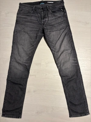 Replay Jeans - Säljer ett par svarta jeans från Replay med rak passform och klassisk femficksdesign. Jeansen är i gott skick och är tillverkade i ett mjukt bomullsmaterial med lite stretch för extra komfort. Perfekta för en avslappnad och stilren look.