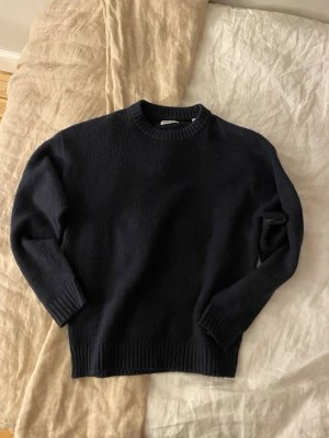Mörkblå stickad crewneck tröja - Mörkblå stickad crewneck tröja från Jack & Jones med ribbade muddar vid ärmslut och nederkant. Klassisk och enkel design som passar perfekt till jeans. Skön och varm för kyligare dagar. Nästan aldrig använd.