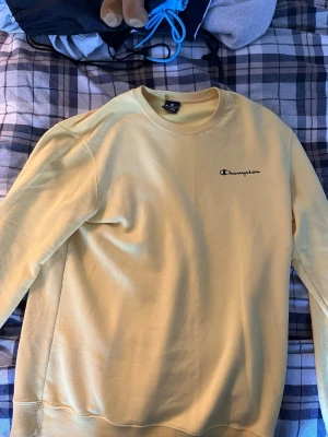Gul sweatshirt från Champion XL - Säljer en ljusgul sweatshirt från Champion i storlek XL. Tröjan har rund halsringning, lång ärm och Champion-logga broderad på bröstet. Tröjan är i xl men passar dig som har L. Den är använd fåtal gånger och finns inga defekter på att den är använd. Skriv vid funderingar!!!!
