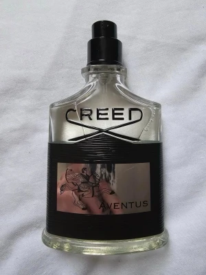 Creed Aventus Eau de Parfum 50ml - Creed Aventus Eau de Parfum är en exklusiv herrdoft i en elegant, genomskinlig glasflaska med svart etikett och silverdetaljer. Flaskan har en unik form och kommer med original svart kartong med silverlogga och ryttare. Volymen är 50 ml.