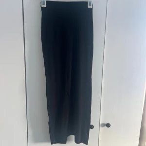 Svart långkjol med slit - En svart långkjol i enkel och stilren design. Kjolen har en rak passform och en slits baktill för extra rörelsefrihet. Perfekt att matcha med både sneakers och boots för en trendig look. Bortklippta lappar men den passar xs/s! Längd: 92 cm 