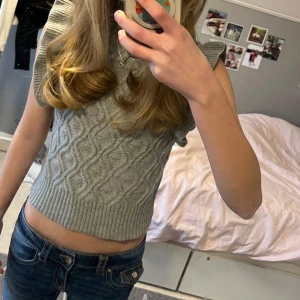 Grå stickad topp från Shein 💓 - Säljer en grå stickad topp från Shein med ett snyggt flätmönster. Toppen är ärmlös med volangdetaljer vid axlarna och har en ribbad kant vid midjan. Tröjan säljs billigt och vill gärna ha snabb affär 🫶🏻 - Priset kan diskuteras