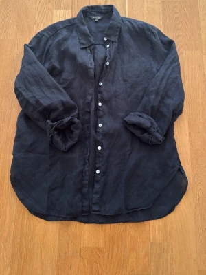 Svart linneskjorta med knappar - Snygg svart skjorta i linne från Massimo dutti med klassisk krage och vita knappar framtill. Skjortan har lång ärm som kan vikas upp för en mer avslappnad look. Perfekt för dig som gillar en stilren och enkel vibe.