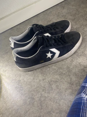 Mörkblå Converse CONS sneakers - ‼️skorna tvättas innan postningen ‼️Säljer ett par mörkblå  Converse CONS sneakers i mocka med vita detaljer och klassisk stjärnlogga på sidan. Skorna har vita sulor och svarta skosnören. Perfekta för dig som gillar en clean och tidlös look.