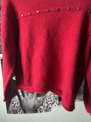 Röd stickad tröja med nitar Mango - Snygg röd stickad tröja från Mango med silverfärgade nitar längs bröstet och axlarna. Tröjan har rund halsringning och långa ärmar. Perfekt för dig som vill ha en enkel men edgy look.