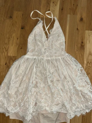 Vit spetsklänning studentklänning - Säljer en superfin vit kortklänning med spetsdetaljer och v-ringning. Perfekt till studenten! Klänningen har tunna axelband som korsas i ryggen och ett luftigt, volangigt kjol. Från Toby