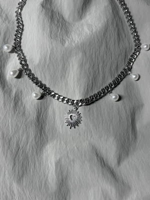 Statement Silver Pearl & Heart Necklace - Ett handgjort, modernt halsband som kombinerar lyster från pärlor med en skulptural hjärtdetalj. 40 cm kedja, kan förlängas vid behov. Tillverkat i rostfritt stål. Designat för att sticka ut.
