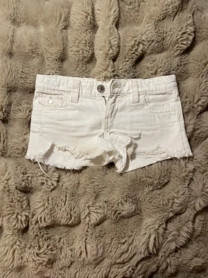 Vita jeansshorts från Gina Trickot  - Säljer ett par vita jeansshorts med fransig kant. Shortsen har två fickor bak. Perfekta för sommaren och ger en snygg look. Själv tycker jag att de upplevs lite större än 146. 