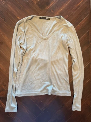 Blågrön ribbad långärmad topp från lager 157 - Säljer en blågrön långärmad topp från lager 157 med ribbad struktur och v-ringad hals. Perfekt för att skapa en enkel och stilren look. Materialet är mjukt och stretchigt, vilket gör den bekväm att bära hela dagen.