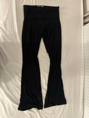 Svarta folded leggings från Lager 157 - Svarta leggings med bootcut passform och bred midja. Materialet är mjukt och stretchigt, perfekt för en avslappnad look. Passar dig som gillar bekväma och stilrena plagg. 