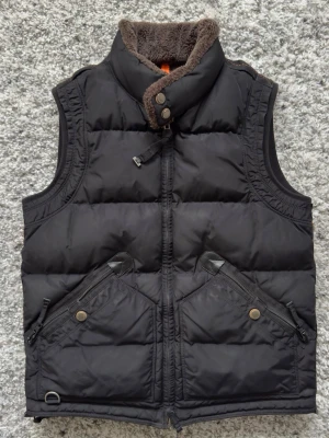 Parajumpers Kobuk Väst - Svart Parajumpers Kobuk väst med päls vid halsen, slutsåld modell och i väldigt fint skick.   Storlek M men passar S, slim modell.  Köpt från Johnells några år sedan för cirka 6000kr. Även kartong från Johnells finns kvar ifall man vill ha den. Priset går att diskuteras vid snabb affär.