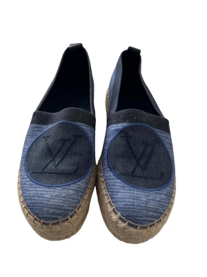 Blå denim loafers från Louis Vuitton - Snygga loafers i blått denimtyg från Louis Vuitton med klassisk LV-logga på ovansidan. Skorna har rund tå och flätad sula i naturfärgad jute som ger en cool kontrast till den blå färgen. Perfekta för dig som gillar exklusiv och trendig stil.