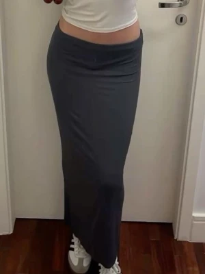 Maxi kjol grå - Säljer en enkel och stilren mörkgrå långkjol i mjukt bomull från Gina tricot. Kjolen har en rak passform och med scrunch på höften. Perfekt attmatcha med crop tops eller stickade tröjor. Superskön och lätt att styla till olika looks.