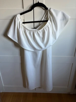Vit offshoulder klänning Vero Moda - Säljer en vit offshoulder klänning från Vero Moda. Klänningen har en lös passform med bred volang upptill och är axelbandslös. Perfekt för sommarens alla tillfällen. Varför inte på studenten?💕