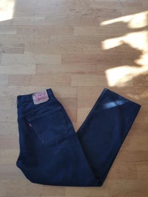 Levi's 505  - Säljer ett par svarta Levi's 505 jeans med rak passform och klassisk femficksdesign. Jeansen har en tydlig läderpatch bak och den ikoniska röda Levi's-taggen på bakfickan. Tillverkade i slitstark denim, perfekta för en avslappnad och tidlös look.