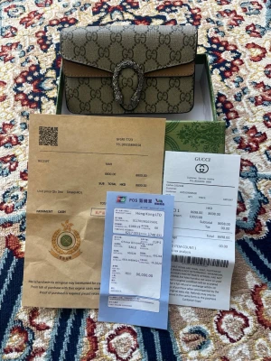 Gucci Dionysus GG Supreme handväska - Snygg Gucci Dionysus handväska i beige GG Supreme canvas med silverfärgad kedja och ikoniskt tigerhuvud-spänne. Väskan har klassiskt monogrammönster och detaljer i ljusbrunt läder. Perfekt för dig som vill ha en lyxig och trendig accessoar.