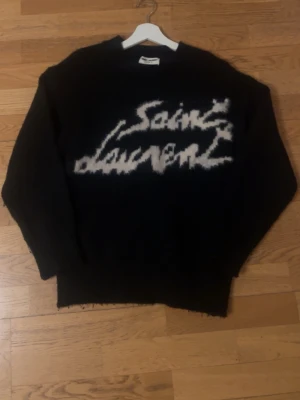 Svart Saint Laurent stickad tröja - Säljer en svart stickad Saint Laurent-tröja i storlek S. Clean och stilren med riktigt bra passform. Funkar perfekt både till vardags och svalare kvällar. Bra skick.